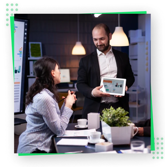 A man and woman sitting at a table, engrossed in their tablet.